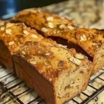 Saftiges Apfelkuchenbrot mit Äpfeln und Zimt auf einem Holztisch.