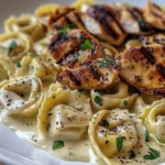 Asiago Tortellini Alfredo mit gegrilltem Hähnchen serviert auf einem Teller.