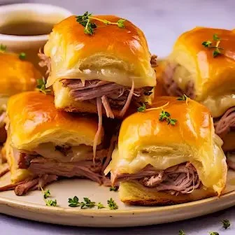 Französische Dip-Slider mit verschiedenen Dips auf einem Tisch präsentiert.