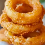 Knusprige bier-batterte Zwiebelringe auf einem Teller serviert.