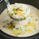 Eine Schüssel gebackene Kartoffelsuppe mit frischen Kräutern und Toastbrot.