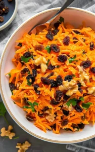 Bunter Karotten-Rosinen-Salat mit frischen Zutaten auf einem Teller angerichtet.