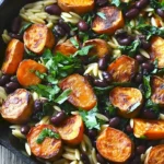 Ultimatives Butternut-Kürbis-Orzo mit Würstchen und Spinat auf einem Teller