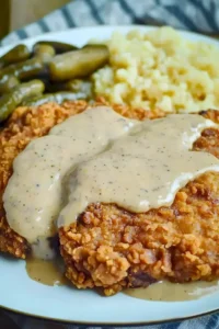 Hähnchen-frittiertes Rindersteak auf einem Teller, serviert mit Beilage.