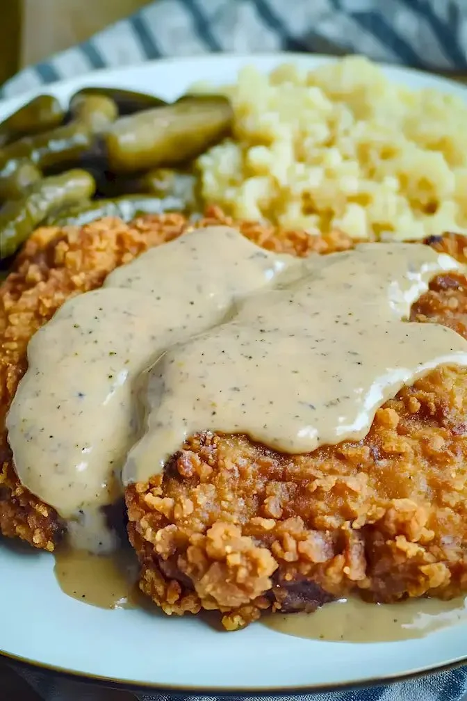 Hähnchen-frittiertes Rindersteak auf einem Teller, serviert mit Beilage.