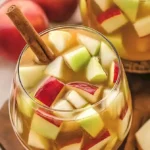 Karamell-Apfel-Sangria in einem Glas, dekoriert mit Apfelscheiben und Karamellsoße.
