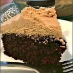 Schokoladen-Erdnussbutter-Verrückter Kuchen auf einem Teller dekoriert mit Erdnüssen.