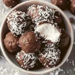 Schokoladen Kokos Kugeln auf einem Teller, perfekt zum Naschen.