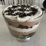 Schokoladen Trifle mit Schichten aus Schokolade, Sahne und Keksen in einem Glas serviert.