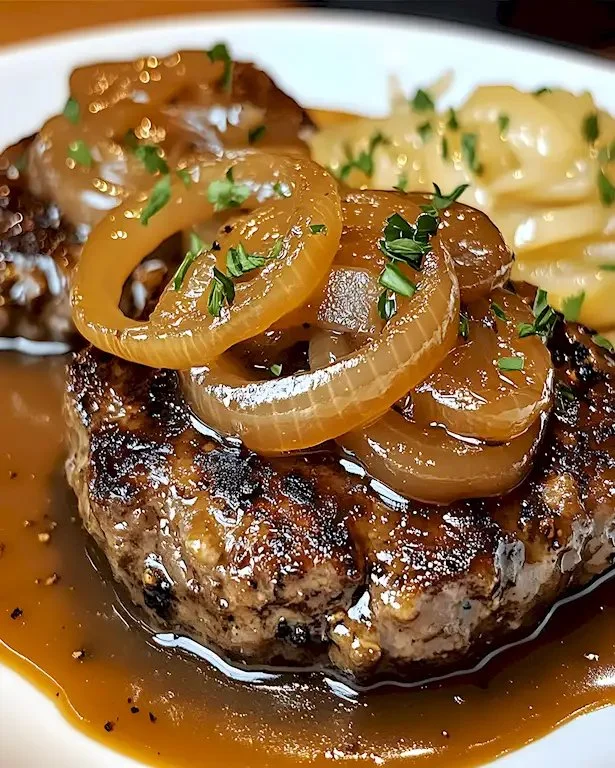 Leckeres Hamburger Steak mit Zwiebelfondue auf einem Teller serviert