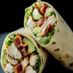 Hähnchen Wrap mit gebratenem Hähnchen, Avocado und Dijon-Sauce auf einem Teller.
